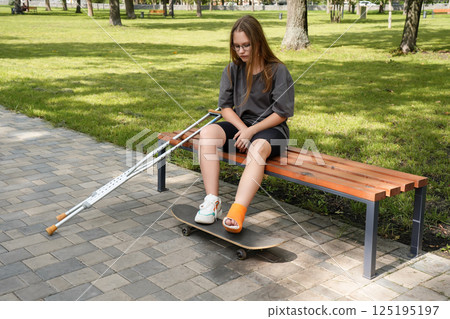 Resting on a park bench, a girl clutches her skateboard, her pensive gaze suggesting an internal struggle with obstacles that test her resilience 125195197