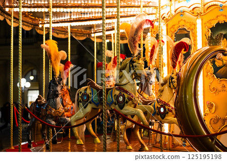 Colorful carousel horses with feathers in nighttime amusement park 125195198