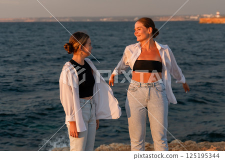 Women Friends Beach Sunset, Two friends enjoy sunset by the sea, creating lasting memories. Women Friends Beach Sunset, Two friends enjoy sunset by the sea, creating lasting memories. 125195344