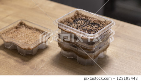 Stacked plastic containers with watered seeds of micro greens on jute mats 125195448
