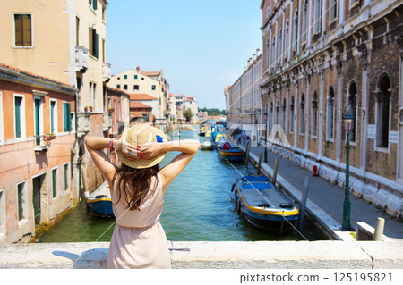 beautiful girl in a hat stands near a canal in Venice, Italy 125195821