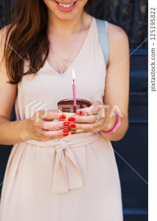 a girl with a cake and a candle is standing near the door 125195822