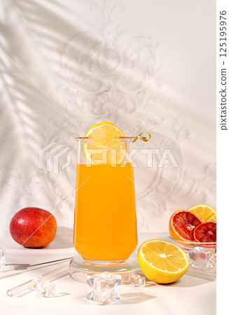 Orange juice and oranges on elegant kitchen table with long hard shadows. Modern still life with citrus fruits, minimal detox diet concept, summer vitamin drinks, healthy lifestyle advertisement 125195976