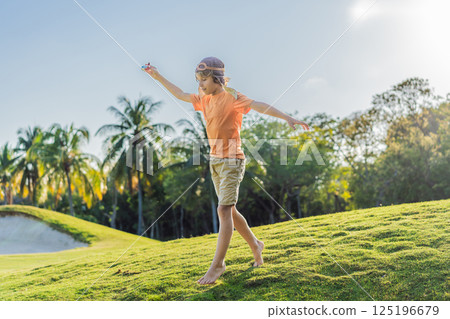 Boy wearing a pilot hat running through the grass with a toy airplane, dreaming of adventures. Childhood, imagination, and freedom concept Boy wearing a pilot hat running through the grass with a toy airplane, dreaming of adventures. Childhood, imagination, and freedom concept 125196679