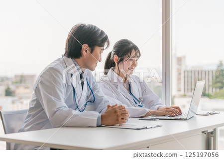 A female trainee doctor receives training while viewing electronic medical records on a computer with a male instructor. A female trainee doctor receives training while viewing electronic medical records on a computer with a male instructor. 125197056