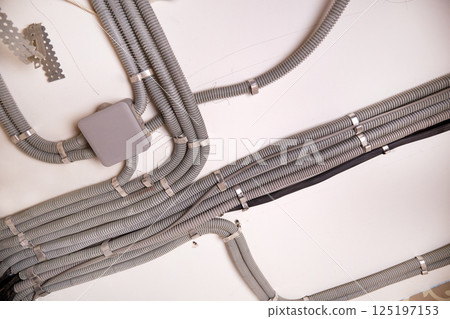 The electrical wires in the protective corrugated cable tube and the junction box are neatly laid on the ceiling 125197153