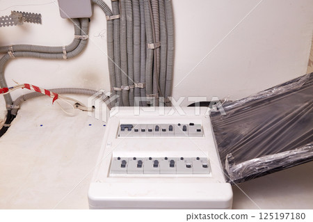 Electrical wires in a protective corrugated pipe on the ceiling and a modular housing on the wall Electrical wires in a protective corrugated pipe on the ceiling and a modular housing on the wall 125197180