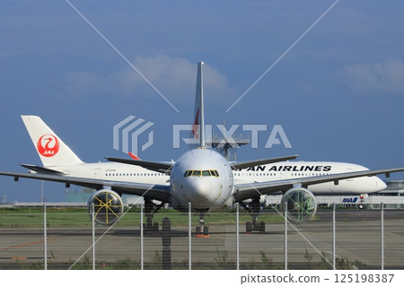 A passenger plane taxiing behind a parked aircraft 125198387