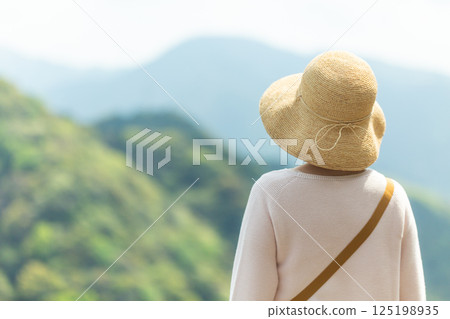 A middle-aged woman looking at the mountains from an observation deck A middle-aged woman looking at the mountains from an observation deck 125198935
