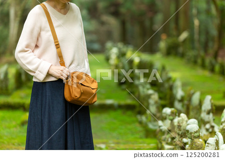 A middle-aged woman sightseeing at a mountain temple with stone Buddha statues A middle-aged woman sightseeing at a mountain temple with stone Buddha statues 125200281