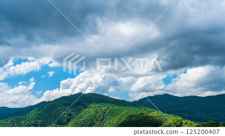Many white clouds in the blue summer sky and fresh green mountains Many white clouds in the blue summer sky and fresh green mountains 125200407