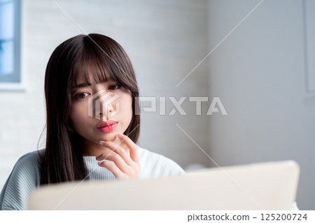 A young woman looking at a computer and worrying A young woman looking at a computer and worrying 125200724