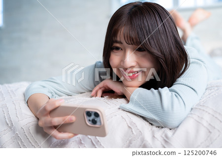 A young woman lying face down with a smartphone 125200746
