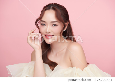 A beautiful young Asian woman with clean, fresh skin against a pink background. Skincare, facial treatment, cosmetology, beauty, and spa. An elegant portrait of an Asian woman. 125200885