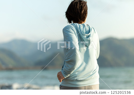 傍晚在沙灘上跑步的中年婦女 傍晚在沙灘上跑步的中年婦女 125201536