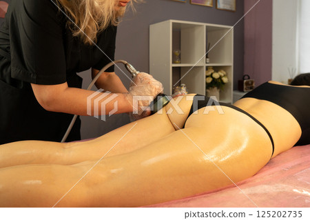 Beautician performs radiofrequency treatment on client's gluteal area. Beautician performs radiofrequency treatment on client's gluteal area. 125202735