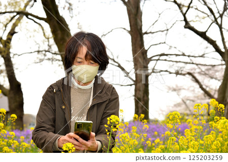 Senior taking photos of flowers with a mobile phone 125203259