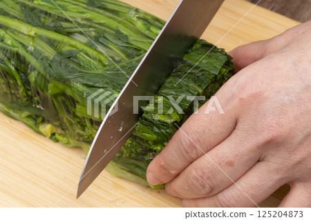 Remove the solidified vegetable terrine from the mold and cut it with a knife. Remove the solidified vegetable terrine from the mold and cut it with a knife. 125204873
