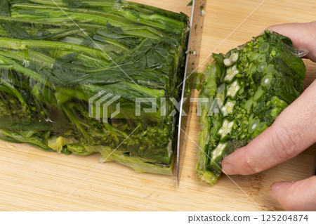 Remove the solidified vegetable terrine from the mold and cut it with a knife. 125204874