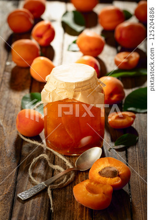 Apricot jam and fresh fruit on an old wooden table. Apricot jam and fresh fruit on an old wooden table. 125204886