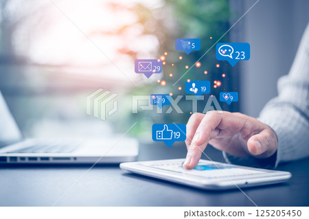 Social media and digital online concept. Businesswoman working with tablet in corporate office with notification icons of like, message, comment and star above smartphone screen. Social media. Social media and digital online concept. Businesswoman working with tablet in corporate office with notification icons of like, message, comment and star above smartphone screen. Social media. 125205450