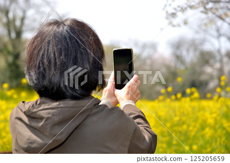 Senior taking photos of flowers with a mobile phone 125205659
