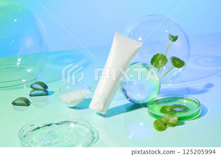Transparent balloons, glass balls and petri dishes filled with liquids are placed around cosmetic tubes, presented on a green background. Gotu kola and aloe vera are scattered around for decoration. Transparent balloons, glass balls and petri dishes filled with liquids are placed around cosmetic tubes, presented on a green background. Gotu kola and aloe vera are scattered around for decoration. 125205994