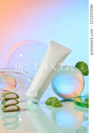 Bubbles of different sizes surround an unlabeled tube. A circular petri dish filled with water. Gotu kola and aloe vera are natural ingredients with many benefits. Gradient background pink and blue. 125205996