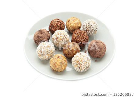 Healthy raw energy balls. Candy vegan balls of dates, nuts and coconut on plate isolated on white background. Top view, concept of useful home-made candies without sugar Healthy raw energy balls. Candy vegan balls of dates, nuts and coconut on plate isolated on white background. Top view, concept of useful home-made candies without sugar 125206883