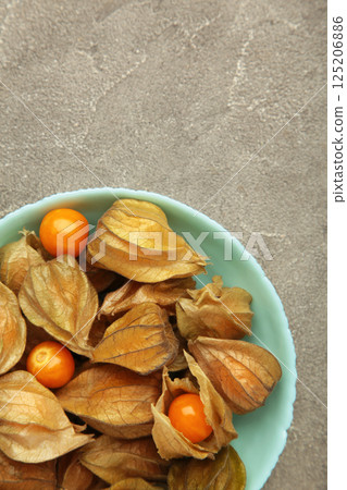 Physalis peruviana fruit on mint plate on grey background. Vertical photo 125206886