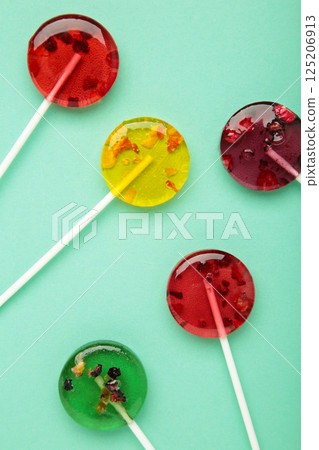 Colorful sweet lollipops with berries on mint background. Vertical photo 125206913