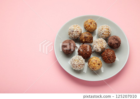 Healthy homemade energy balls with cranberries, nuts, dates and rolled oats on pink background. Space for text Healthy homemade energy balls with cranberries, nuts, dates and rolled oats on pink background. Space for text 125207010