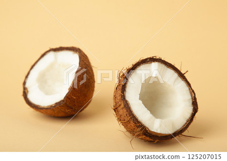 Coconut with half on beige background. Space for text 125207015