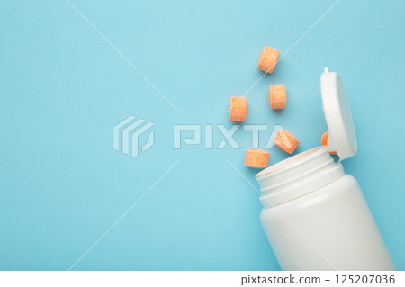 Vitamin C pills with jar on blue background. Space for text 125207036