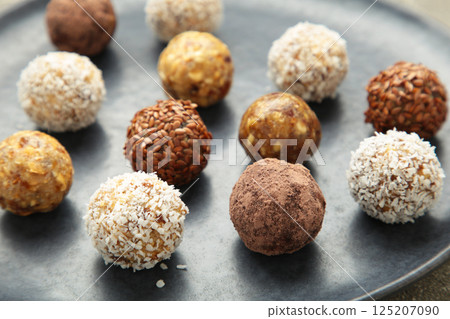 Healthy raw energy balls. Candy vegan balls of dates, nuts and coconut on dark plate. Top view, concept of useful home-made candies without sugar. Vertical photo Healthy raw energy balls. Candy vegan balls of dates, nuts and coconut on dark plate. Top view, concept of useful home-made candies without sugar. Vertical photo 125207090
