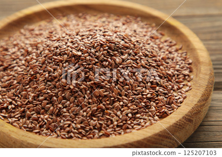 Wooden bowl with flax seeds on grey background. 125207103