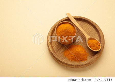 Dry turmeric powder(curcuma) in plate on beige background. 125207113