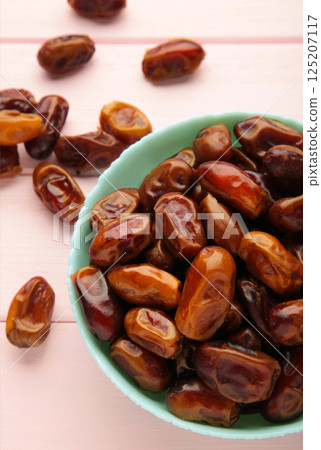 Fresh dates in mint bowl on pink background. Vertical photo 125207117
