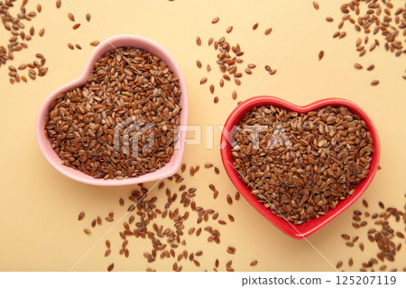 Healthy food. Flax seeds in pink and red heart shaped bowls on beige background. 125207119