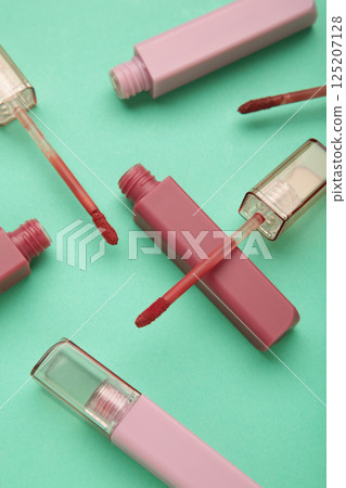 Beautiful lip glosses on a mint background. Vertical photo 125207128