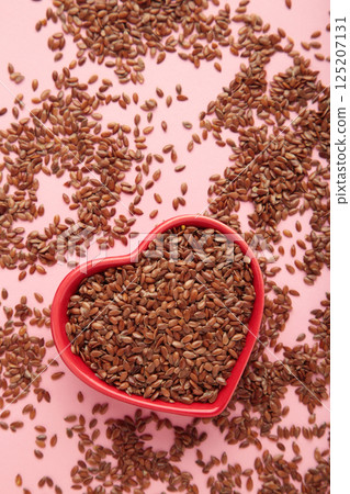 Healthy food. Flax seeds in red heart shaped bowls on pink background. 125207131