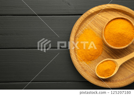 Turmeric (Curcuma) powder on wooden plate on black background Turmeric (Curcuma) powder on wooden plate on black background 125207180