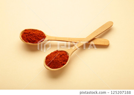 Powder paprika with wooden spoon on beige background Powder paprika with wooden spoon on beige background 125207188