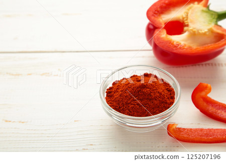 Paprika powder in plate with fresh red pepper on white background. 125207196