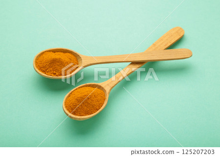 Turmeric in the spoon on mint background Turmeric in the spoon on mint background 125207203