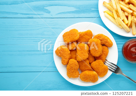 Homemade chicken nuggets and french fries with ketchup on blue wooden background. Space for text 125207221