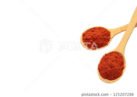 Powder paprika with wooden spoon isolated on white background 125207286
