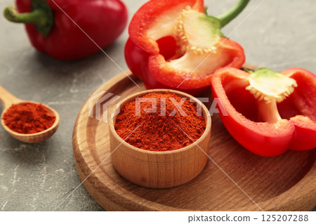 Paprika powder with fresh red pepper on grey background. Paprika powder with fresh red pepper on grey background. 125207288