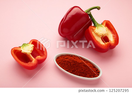 Paprika powder in plate with fresh red pepper on pink background. 125207295