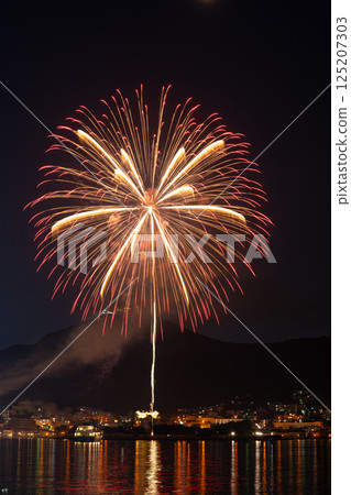 A fireworks display that lights up the mountains and cityscape on a summer night A fireworks display that lights up the mountains and cityscape on a summer night 125207303